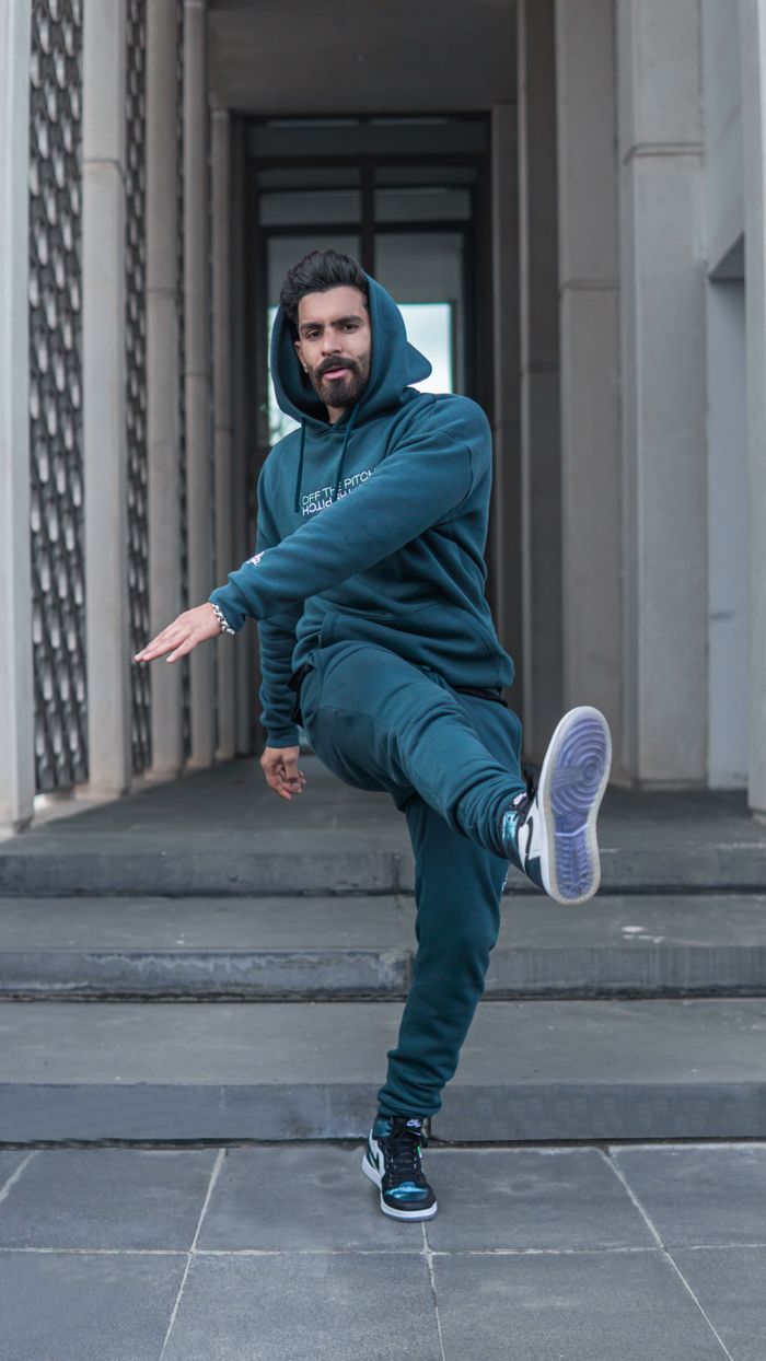 Stylish man in a hoodie and joggers posing on concrete stairs outdoors in Fes, Morocco.